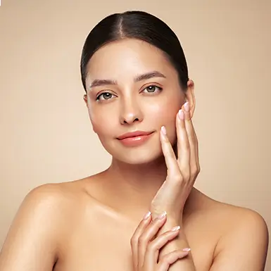 A smiling woman poses with one hand on her face